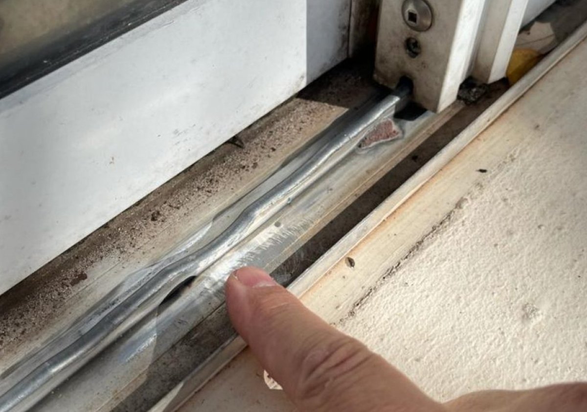 Heavily damaged bent sliding door bottom track requiring replacement